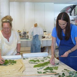 2 Frauen beim Auflegen der Blätter auf Stoff.